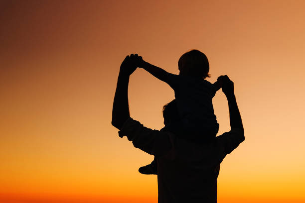 istock Father and son silhouettes at sunset sky. 922365754