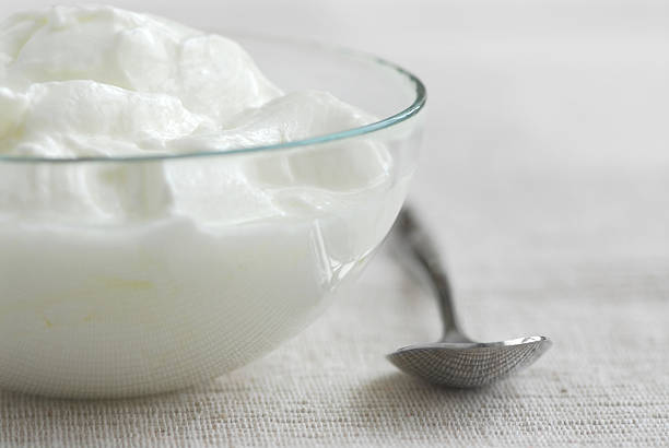 A close up photograph of a bowl of yogurt and a spoon Fresh yogurt served in a clear glass bowl heathy stock pictures, royalty-free photos & images