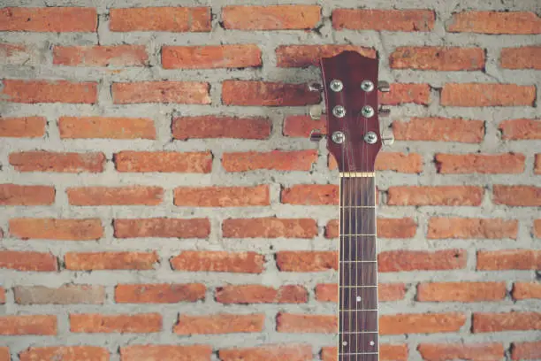 Photo of classical guitar with brick background horizontal