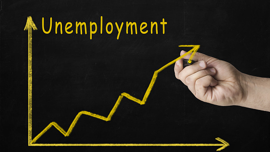 Rising Unemployment Rates. Image of a businessman hand make a chart of unemployment rate with growing arrow on blackboard.