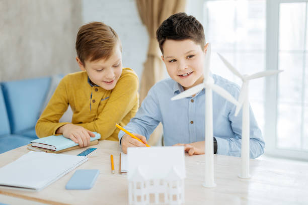 istock Pleasant boy watching his brother draw wind turbine 922375926
