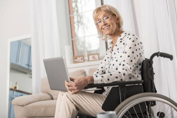 Handicapped mature woman using laptop stock photo