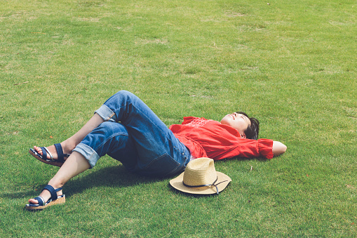 A Japanese woman is resting on green grass in summer.