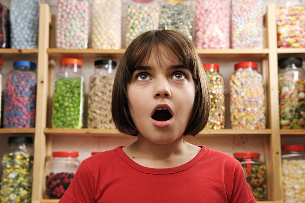 A child looking surprised in a sweet shop young girl looking in awe at rows of sweets confectioner photos stock pictures, royalty-free photos & images