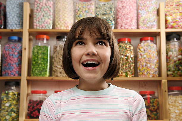 Excited child in a candy store young girl smiling in awe at rows of sweets gawp stock pictures, royalty-free photos & images