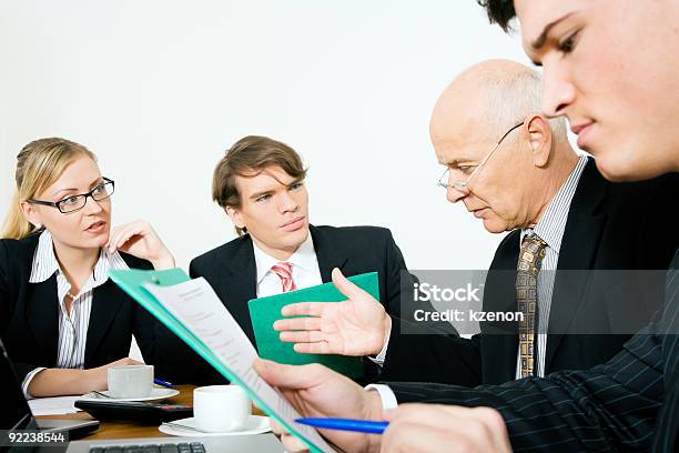 People In Suits Having Meeting Around Table With White Wall Stock Photo - Download Image Now