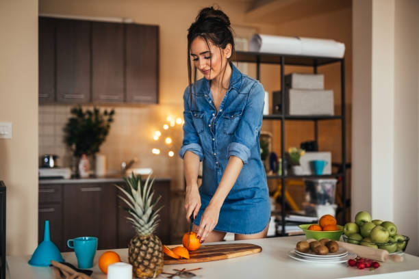 istock Young woman slicing orange in her kitchen 922386928