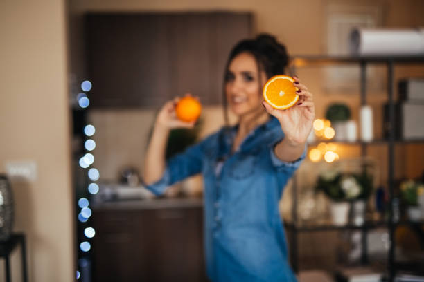 Young woman holding orange fruit in her hands in the kitchen
