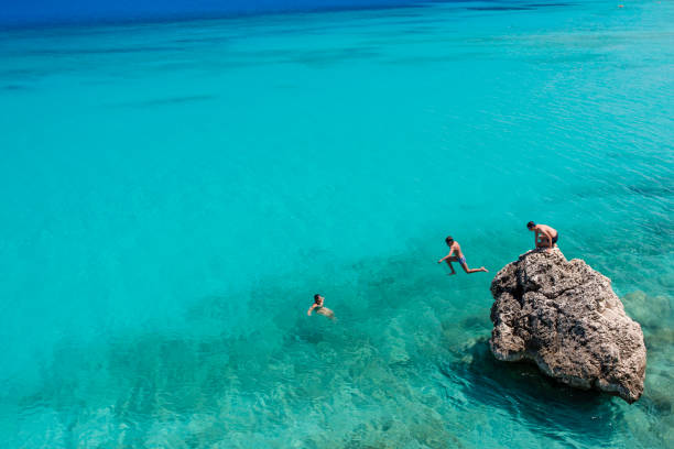 Jumping into turquoise waters of Agios Ioannis Beach at Lefkada, Greece stock photo