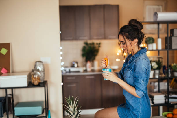 istock Young woman making orange juice in her kitchen 922387778