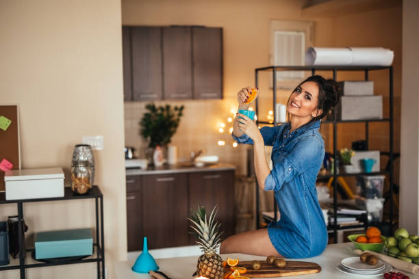 istock Young woman making orange juice in her kitchen 922387786