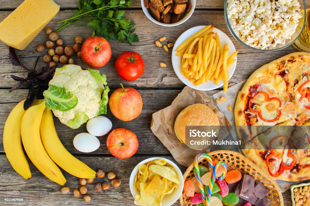 Fastfood and healthy food on old wooden background. Concept choosing correct nutrition or of junk eating. Top view. Unhealthy Eating Stock Photo