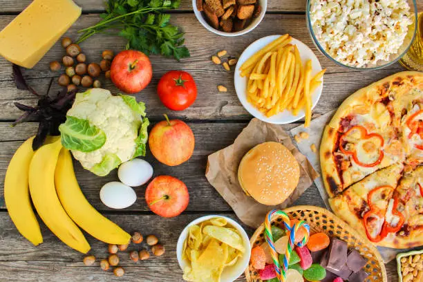 Photo of Fastfood and healthy food on old wooden background. Concept choosing correct nutrition or of junk eating. Top view.