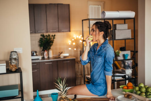 Woman eating apple in her kitchen during lunch break