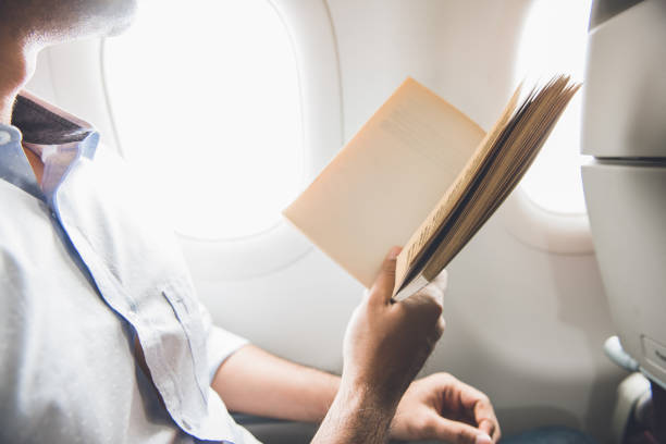 istock Male passenger killing time by reading book while traveling on the airplane 922392426