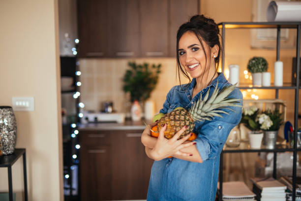 Young woman holding fruit in her hands in the kitchen