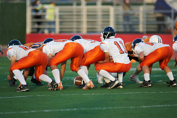 football line stance High school football players in their play stance at the line of scrimmage during a football game offensive line stock pictures, royalty-free photos & images