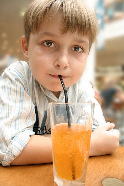 istock child sipping orange soda through straw 92240523