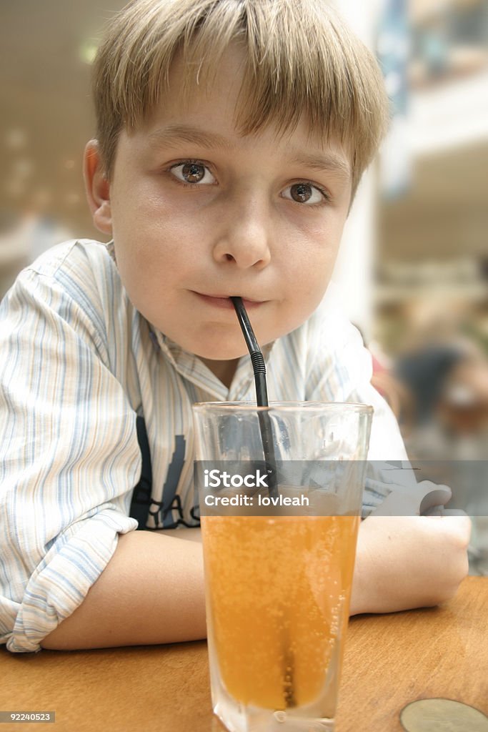 Criança tomar um refrigerante de laranja com palha - Foto de stock de Alimentação Não-saudável royalty-free