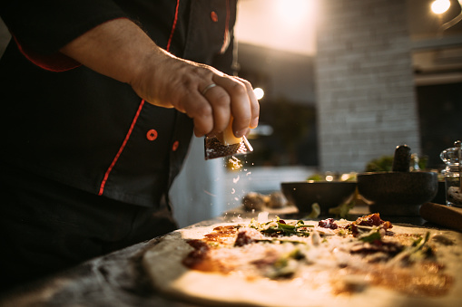Close up photo of an experienced chef preparing pizza