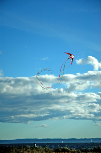 Large, brightly coloured kite flying under a blue sky.