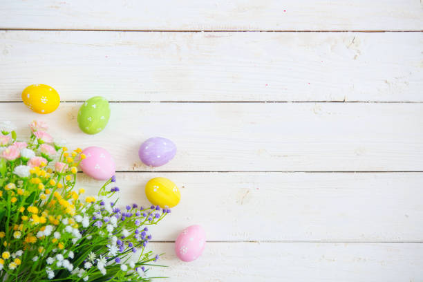 Easter eggs with flowers on white old wooden background