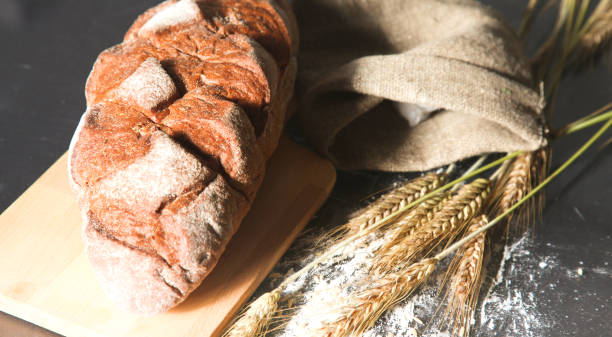 istock rustic crusty bread and wheat ears on a dark wooden table 922412928