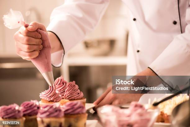 Colpo Ritagliato Di Pasticcere Mettendo Crema Su Cupcakes - Fotografie stock e altre immagini di Pasticciere