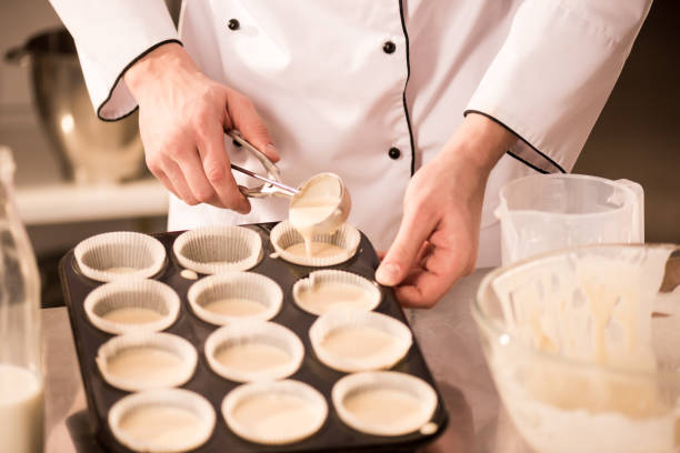 istock cropped shot of confectioner pouring dough into baking forms 922418750