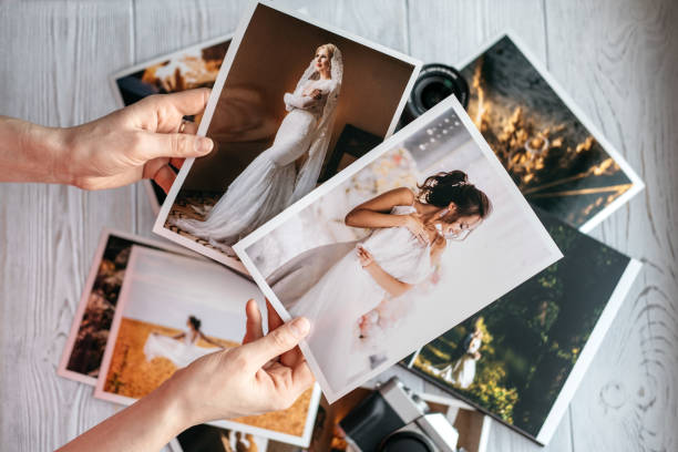 Printed wedding photos with the bride and groom, a vintage black camera and woman hands with two photos Printed wedding photos with the bride and groom, a vintage black camera and woman hands with two photos. Cropped image printing out photos stock pictures, royalty-free photos & images