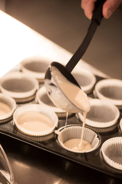 istock cropped shot of confectioner pouring dough into baking forms 922420654