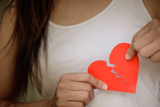 istock Young woman showing red ripped paper heart. Broken hearted on Valentines day concept. 922420708