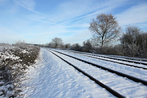 Snow covered railway track from low angle perspective with blue sky