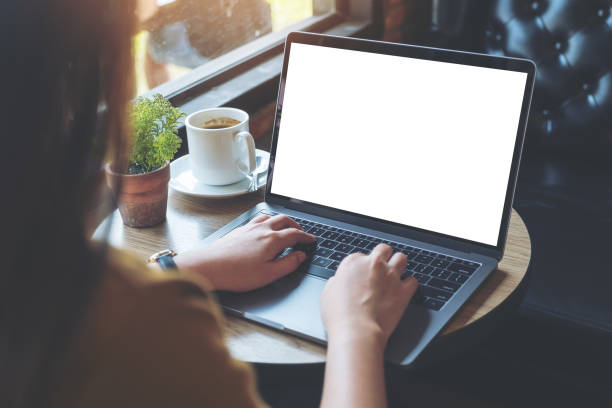 istock Mockup image of woman's hands using and typing on laptop with blank white desktop screen on wooden table in cafe 922421516
