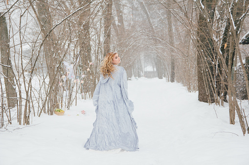 Young beautiful blonde girl in a long skirt outdoors in the winter under the snowfall. Toning.