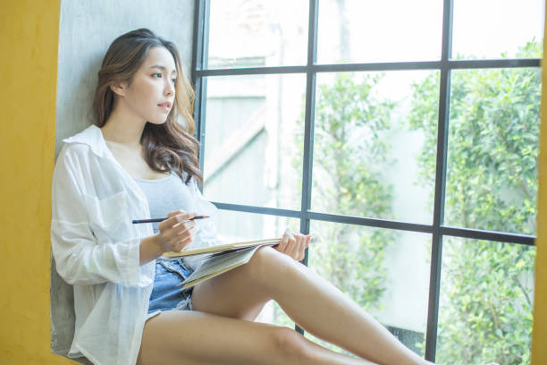 istock Asian woman drawing picture in book. People with education concept. 922425162