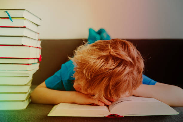 istock little boy tired stressed of reading, doing homework 922433954