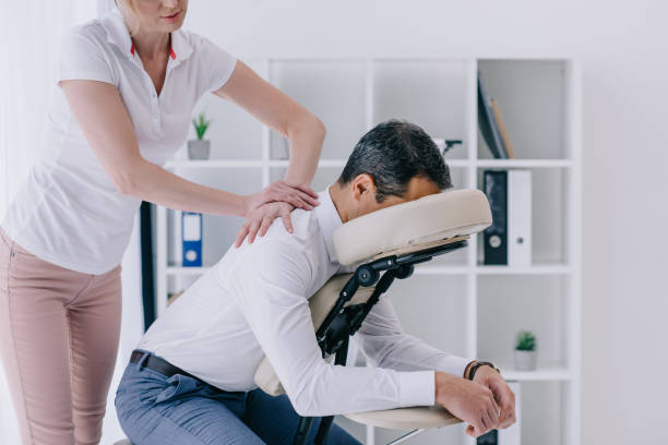 hermosa masajista adulto haciendo asiento masaje para hombre de negocios - chair fotografías e imágenes de stock