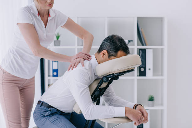 beautiful adult masseuse doing seated massage for businessman - pampering massaging indoors adult imagens e fotografias de stock