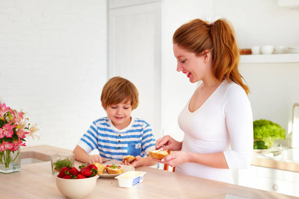 glückliche mutter und sohn, die zubereitung von snacks am morgen in der küche zu hause - family house flash stock-fotos und bilder