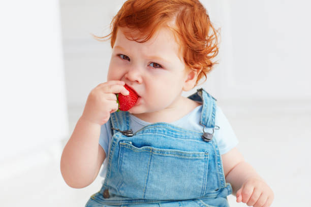 istock cute ginger toddler baby tasting strawberries 922440510