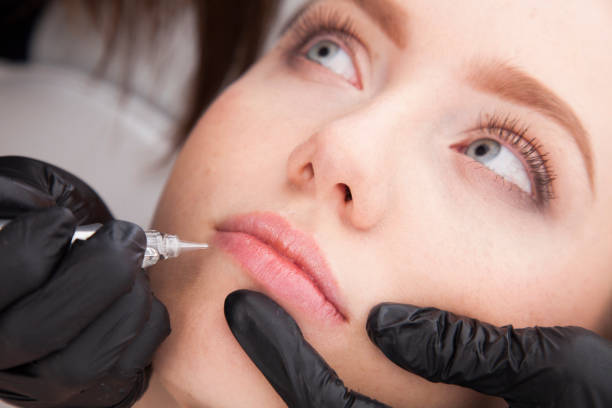 istock Close up on beautician doing a permanent make up of lips. 922447846