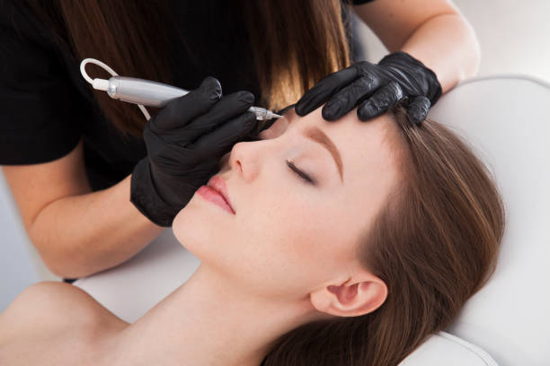 istock Close up on beautician doing permanent make up of eyebrows. 922448076