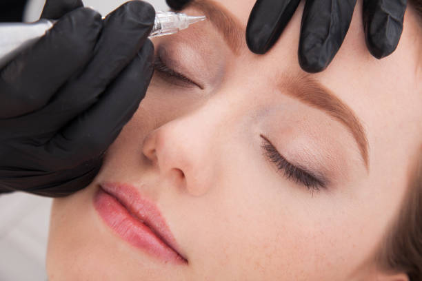 istock Close up on beautician doing permanent make up of eyebrows. 922448220