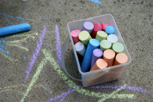 Young Girl Doing Chalk Art On Driveway During COVID-19 Lockdown