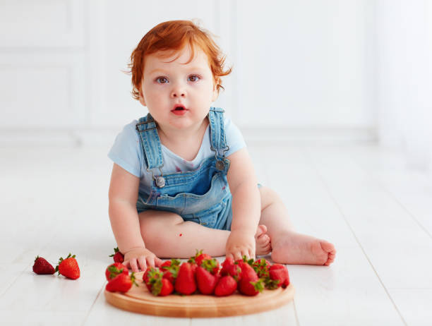 istock cute ginger toddler baby tasting strawberries 922466994