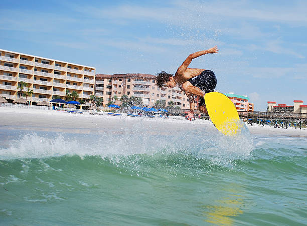 спортивный человек skimboarding объемы воздуха, оставляя след брызги океана - skimboard стоковые фото и изображения