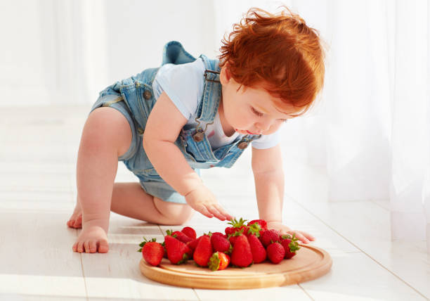 istock cute ginger toddler baby tasting strawberries 922469494