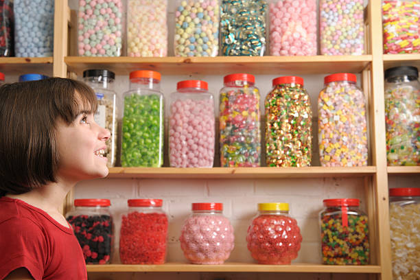 Child staring at shelves in a candy shop young girl smiling at camera in sweet shop gawp stock pictures, royalty-free photos & images