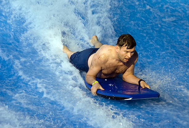 Man riding a board through wave machine stock photo
